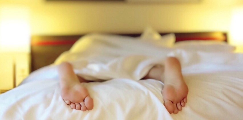 person's feet sticking out of bed sleeping