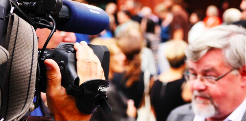 man in front of camera reporting the news