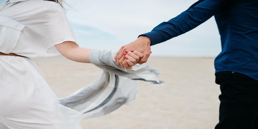 unsplash. man and woman holding hands on the beach during daytime