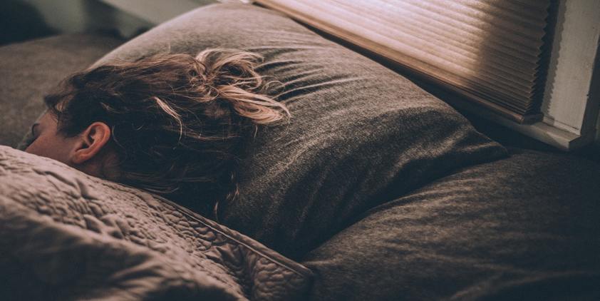 unsplash, woman sleeping under grey covers.