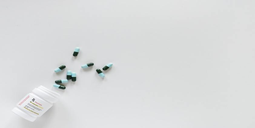 unsplash. blue and green pills coming out of bottle