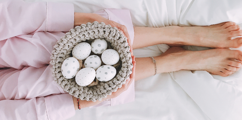 Woman laying in bed with basket of Easter eggs
