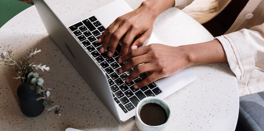 A woman's hands typing on a laptop keyboard
