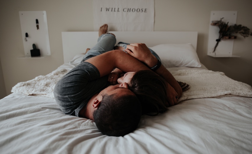 A man and woman cuddle in bed
