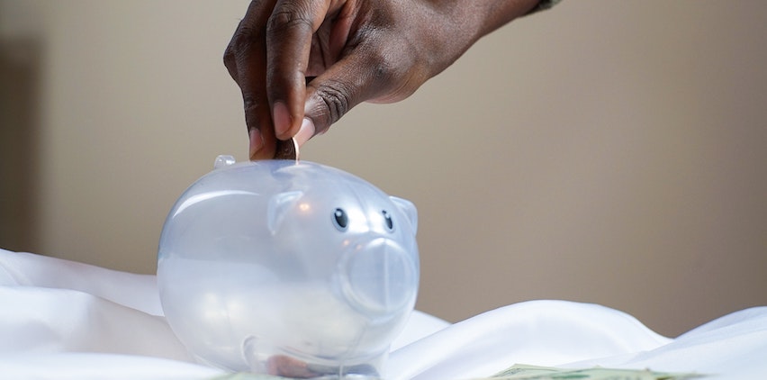 A woman putting money in her piggy bank