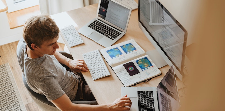 A man working at a desk with computers and books