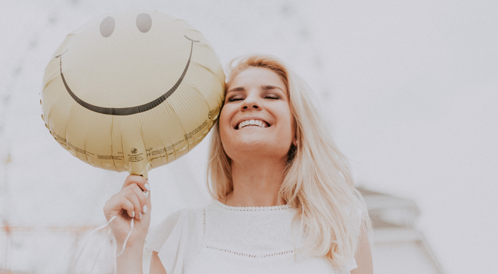 A woman smiling with a smiley face balloon